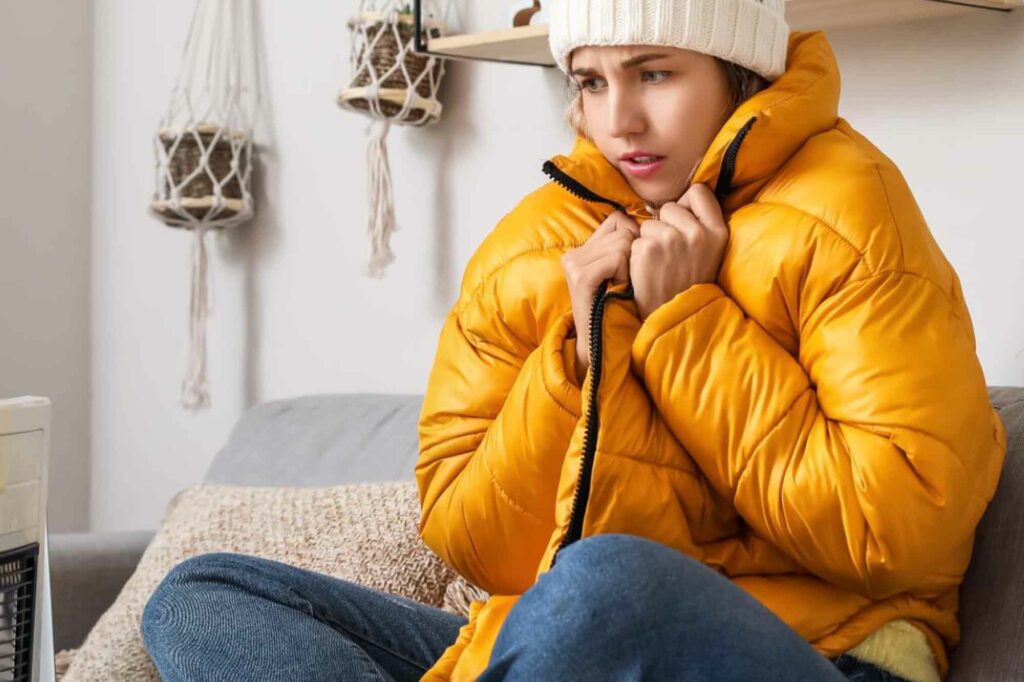 Une femme qui a froid et est en doudoune dans sa maison